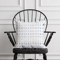 Decorative pillow with a blue and white pattern on a black chair against a white paneled wall.