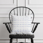 Decorative pillow with a blue and white pattern on a black chair against a white paneled wall.